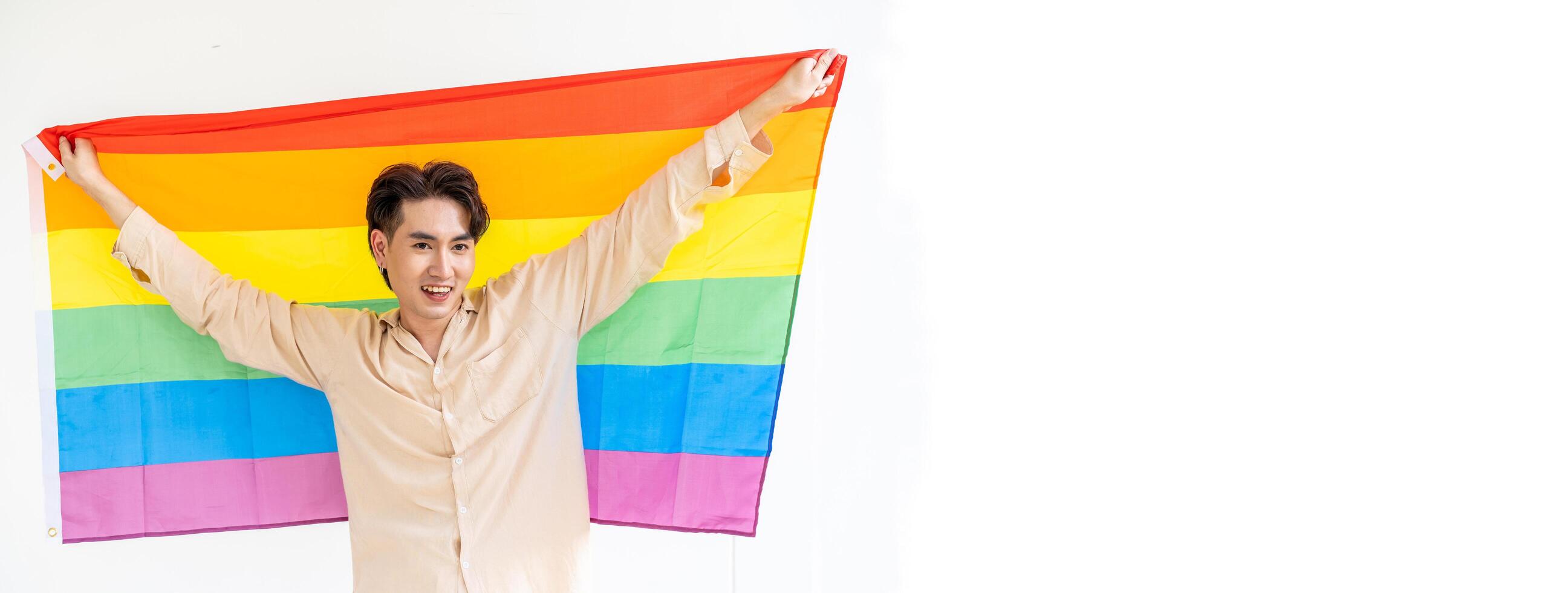 Portrait of transgender or gay man smiling in front of camera with pride rainbow flag isolated on white background with copy space. People lifestyle fashion lgbtq concept photo