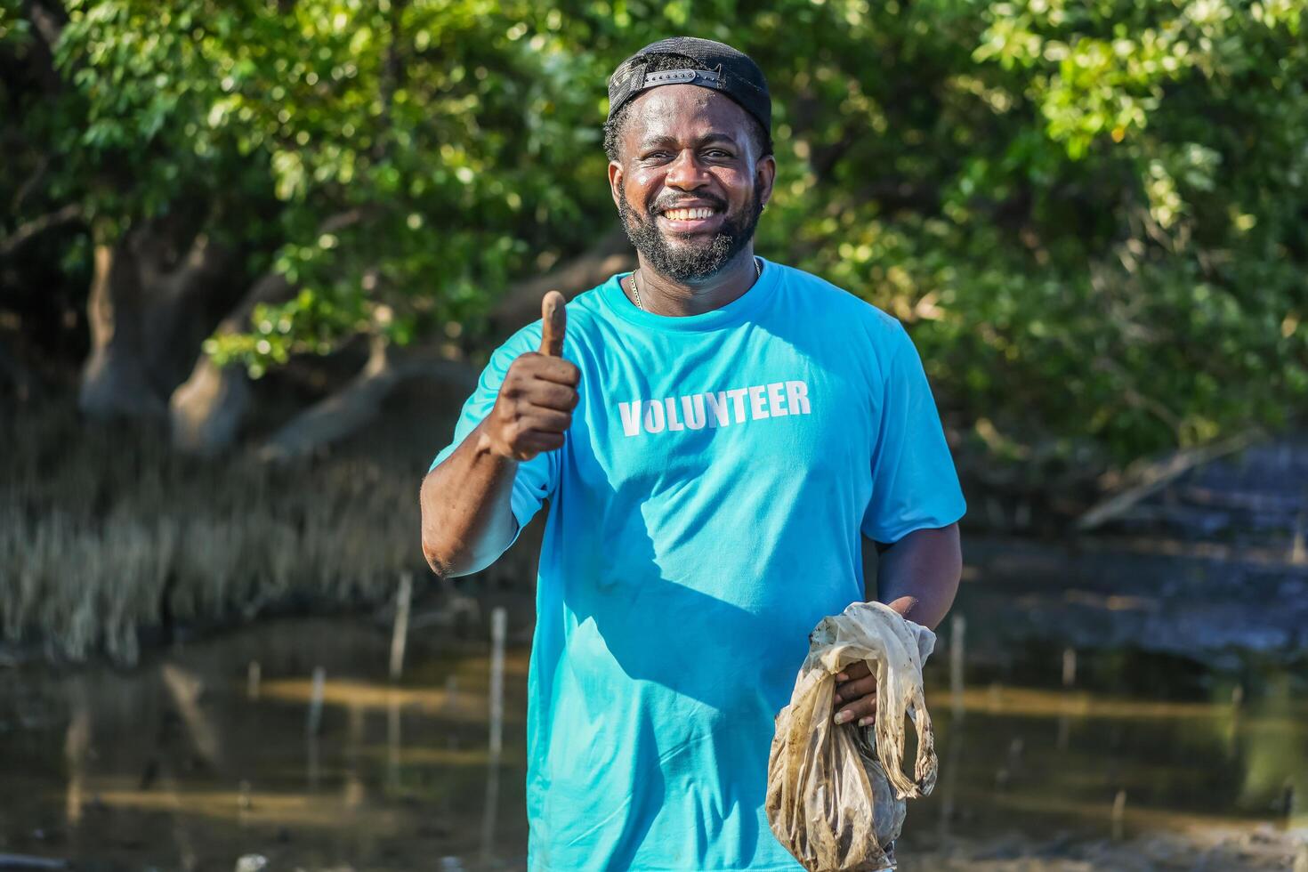 African American men volunteer thumbs up after helpers planting trees in mangrove forest for environmental protection and ecology, reduce global warming. photo