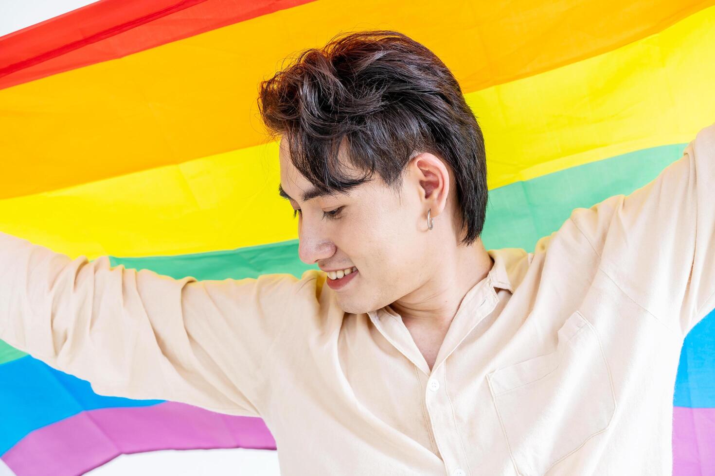 Portrait of transgender or gay man smiling in front of camera with pride rainbow flag isolated on white background with copy space. People lifestyle fashion lgbtq concept photo