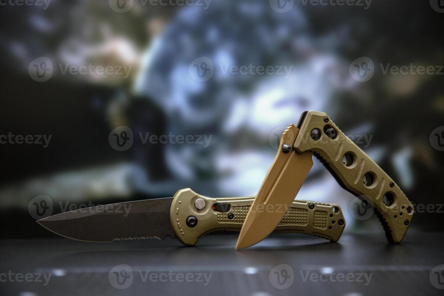 Khaki military pocket folding knives. Compact metal sharp knife with a folding blade. Blurred back. photo