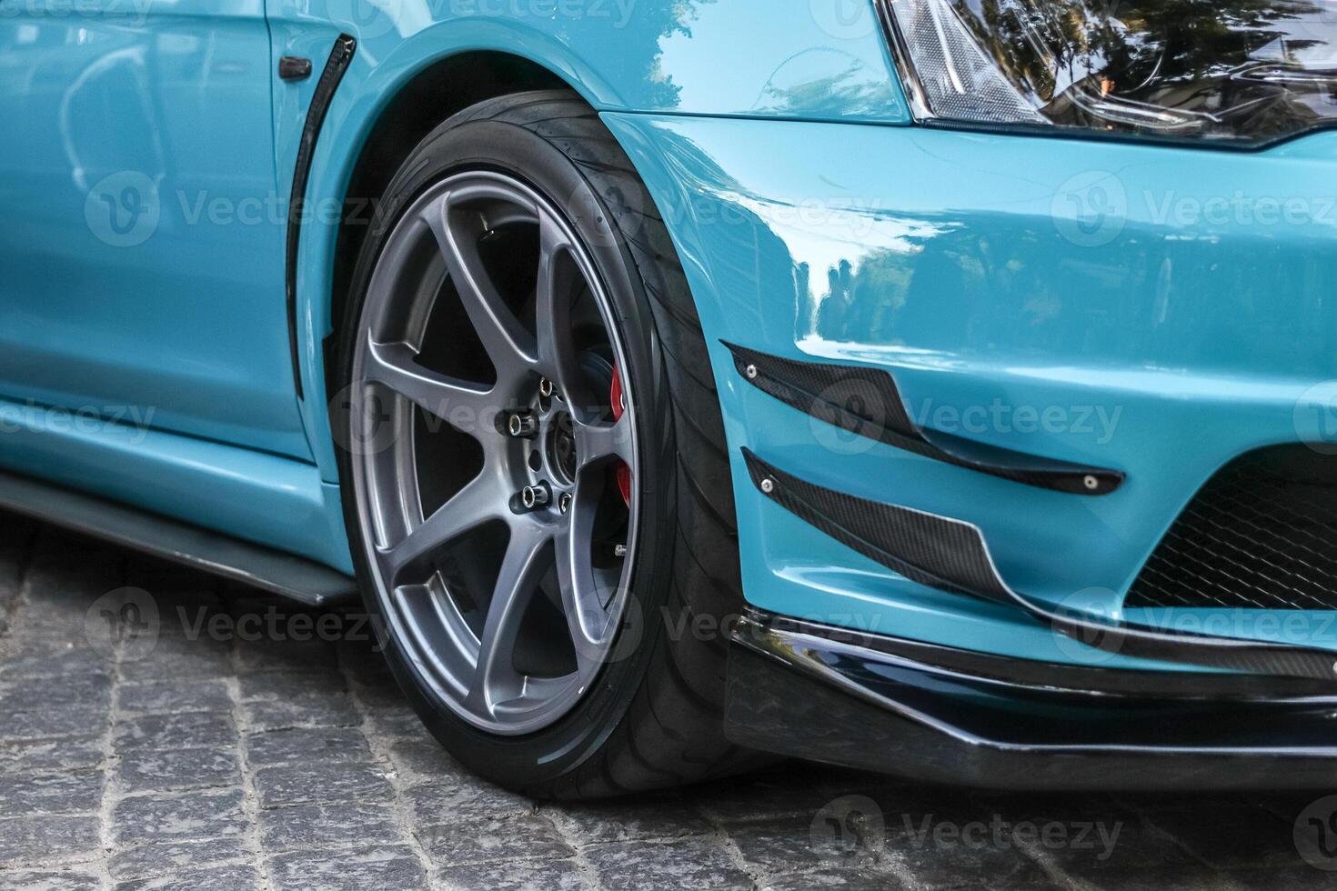 Close up of a wheel of a sports car. Gray car rim with low profile rubber. Blue sports car. photo