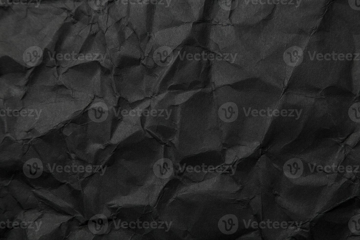 Texture of black crumpled paper. Dark paper background with chaotic bends. A sheet of black wrinkled paper photo