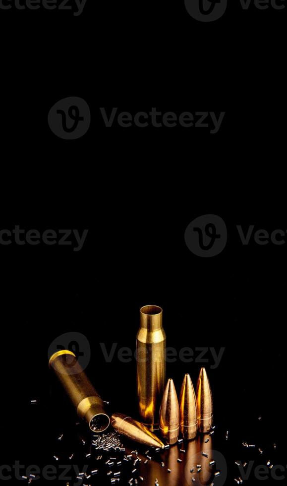 Close-up of disassembled rifle cartridges. Bullet isolated on black background with reflexion. Granulated gunpowder. photo