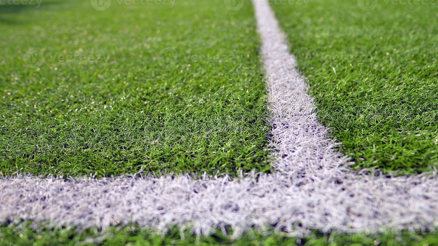 Artificial football turf with a white dividing line. Texture of Perfect green lawn on the football field. photo