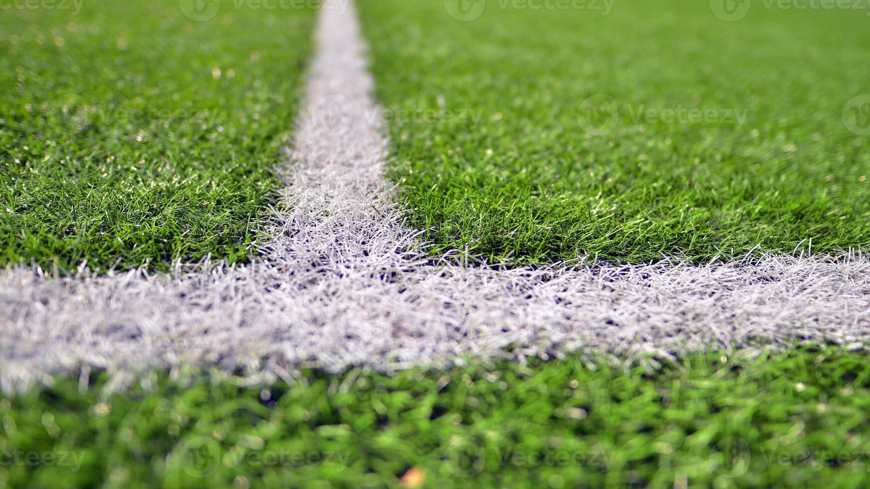 Artificial football turf with a white dividing line. Texture of Perfect green lawn on the football field. photo