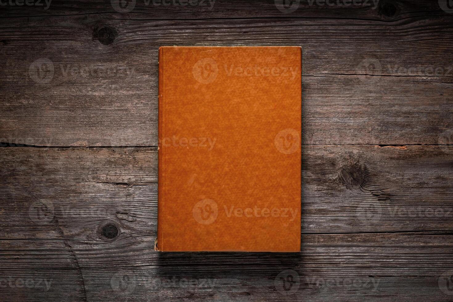 Closed book on vintage wooden background. Old book on the wooden table. Closed book with empty cover laying on wooden table. photo