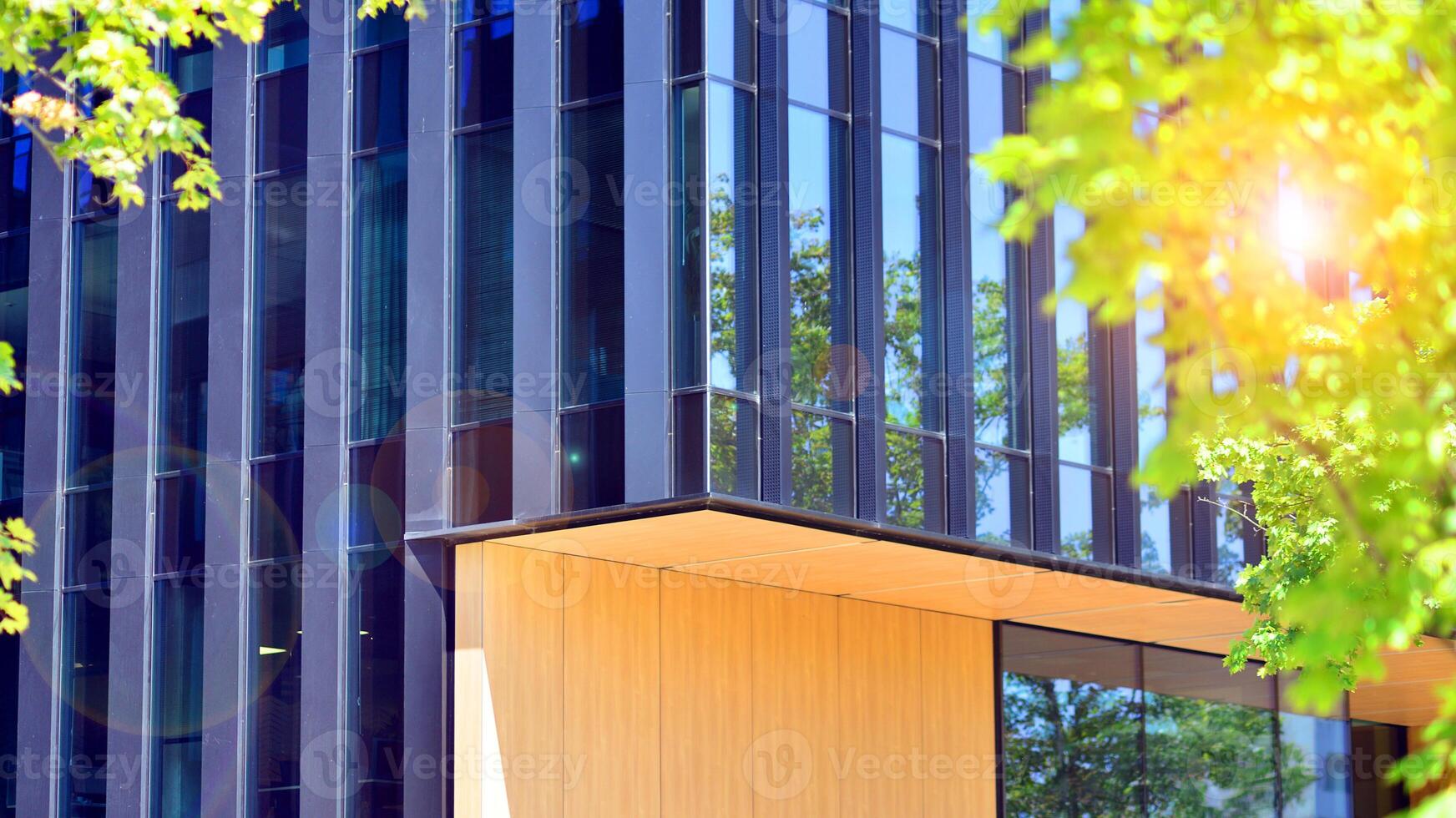 City life, urban landscape and ecology. Modern office complex with glass facades and smooth lines against backdrop of green trees, concept of modern architecture. Organically building into nature. photo
