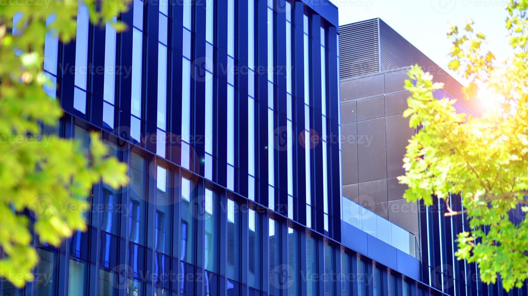 City life, urban landscape and ecology. Modern office complex with glass facades and smooth lines against backdrop of green trees, concept of modern architecture. Organically building into nature. photo