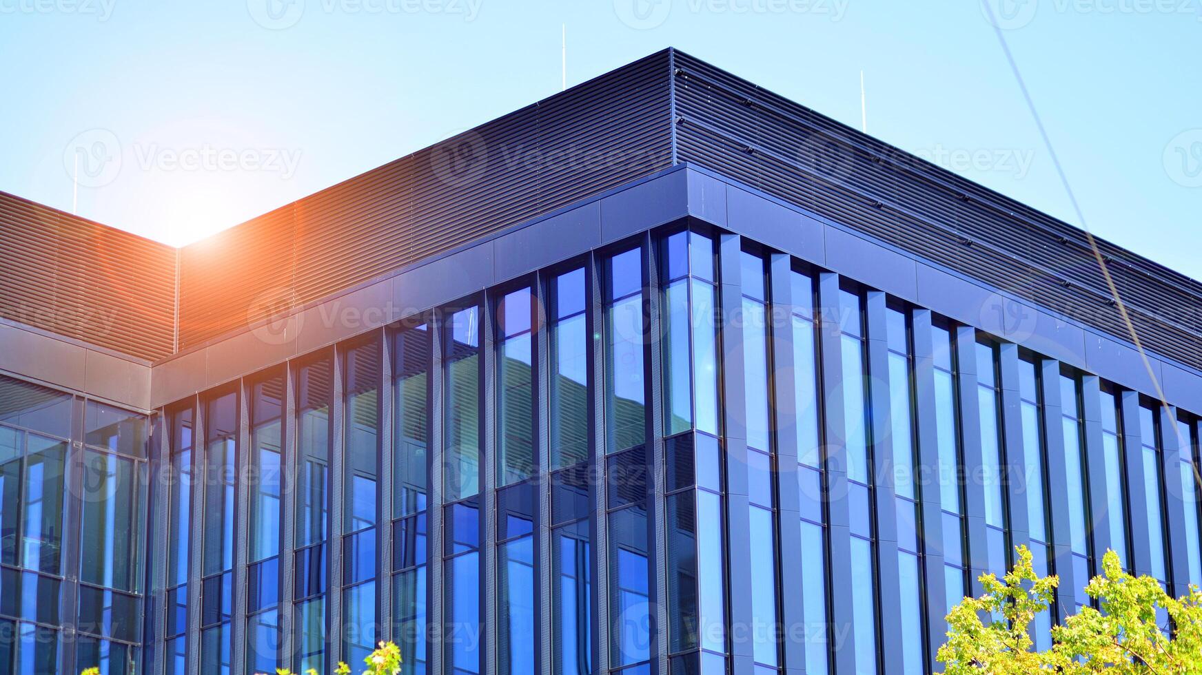 City life, urban landscape and ecology. Modern office complex with glass facades and smooth lines against backdrop of green trees, concept of modern architecture. Organically building into nature. photo