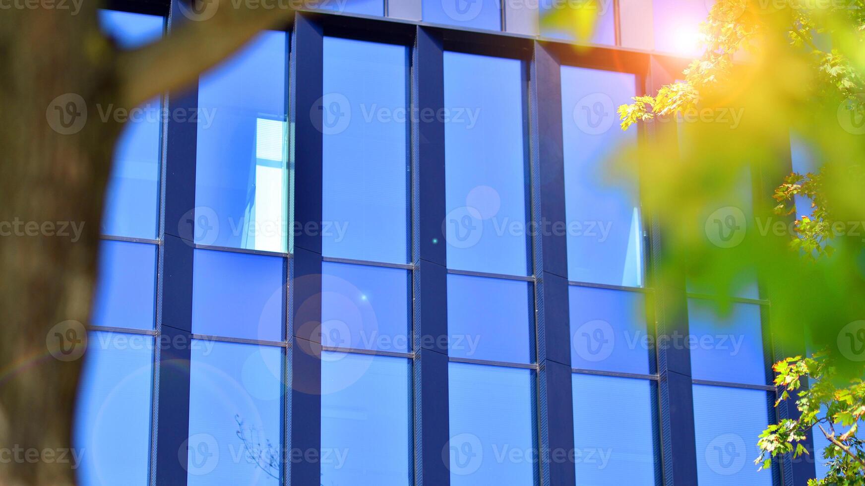 City life, urban landscape and ecology. Modern office complex with glass facades and smooth lines against backdrop of green trees, concept of modern architecture. Organically building into nature. photo