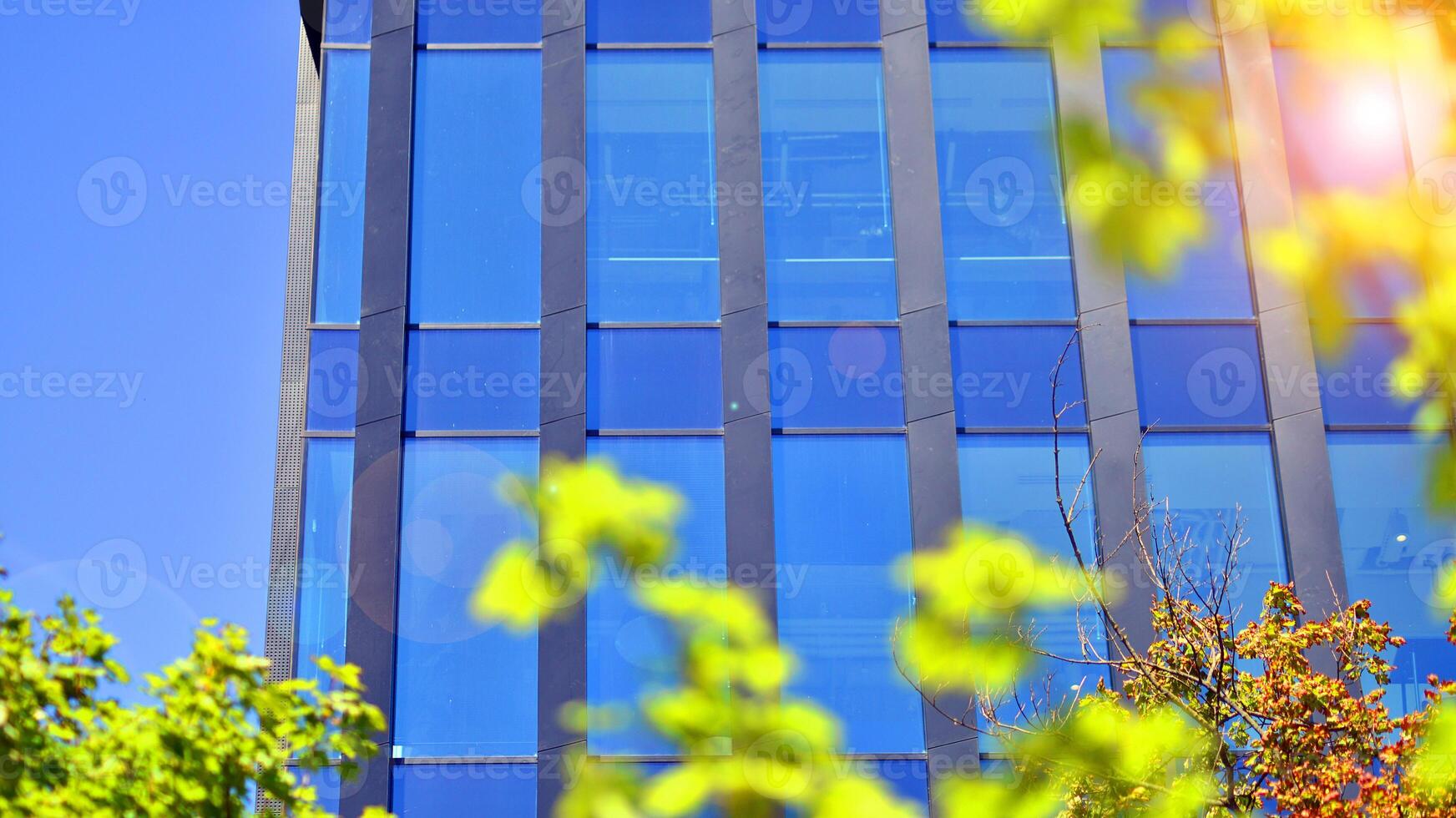 City life, urban landscape and ecology. Modern office complex with glass facades and smooth lines against backdrop of green trees, concept of modern architecture. Organically building into nature. photo