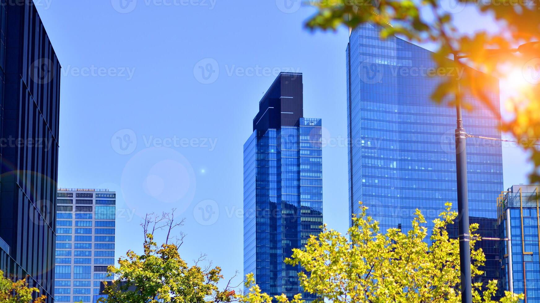 City life, urban landscape and ecology. Modern office complex with glass facades and smooth lines against backdrop of green trees, concept of modern architecture. Organically building into nature. photo