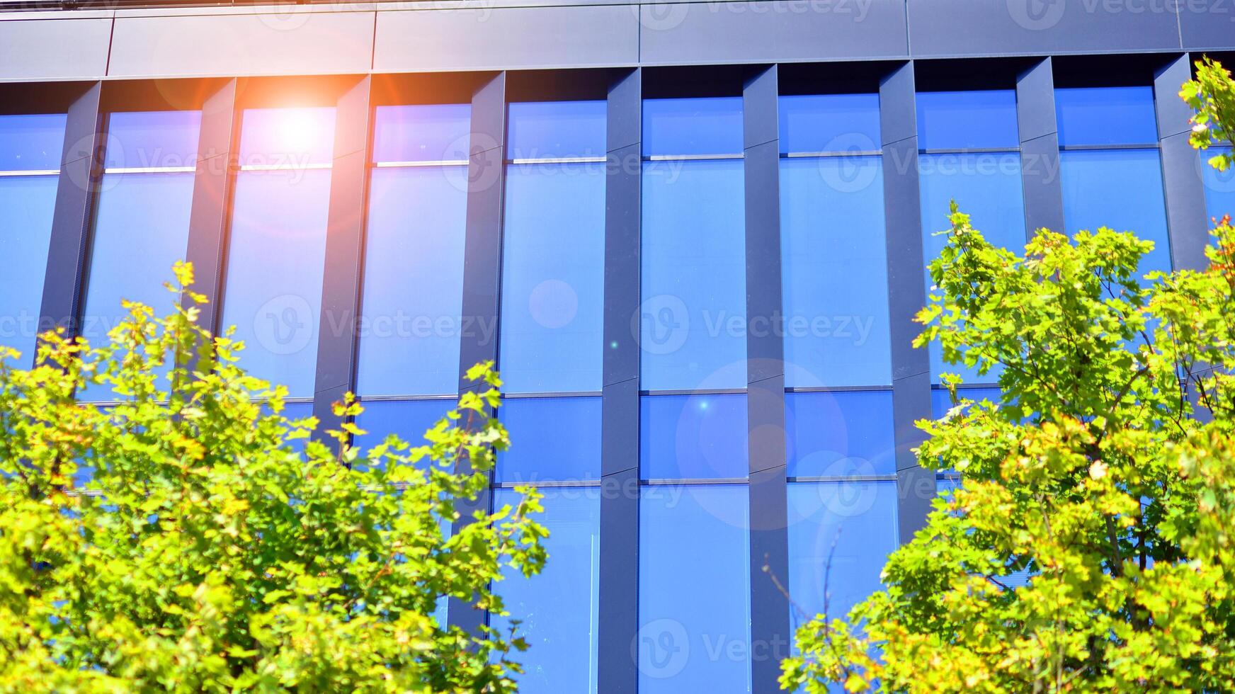 City life, urban landscape and ecology. Modern office complex with glass facades and smooth lines against backdrop of green trees, concept of modern architecture. Organically building into nature. photo