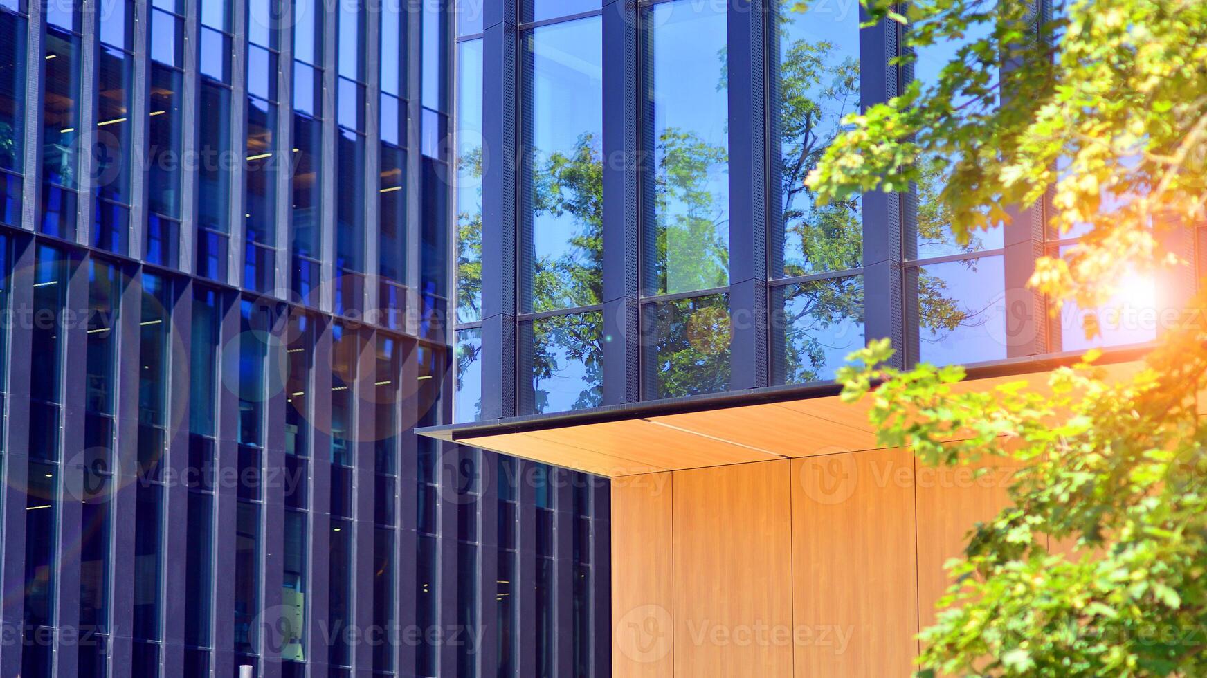 City life, urban landscape and ecology. Modern office complex with glass facades and smooth lines against backdrop of green trees, concept of modern architecture. Organically building into nature. photo