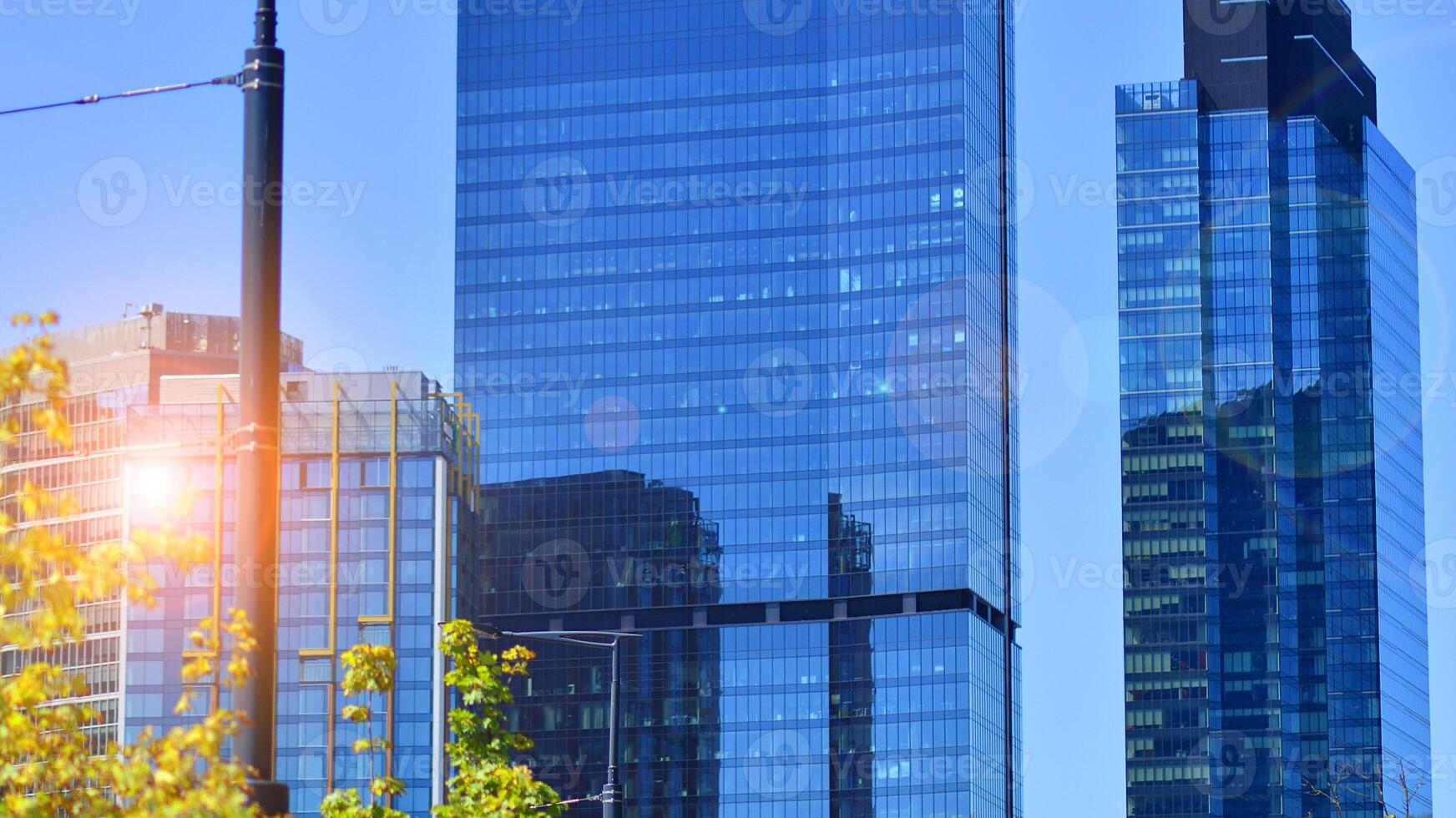 City life, urban landscape and ecology. Modern office complex with glass facades and smooth lines against backdrop of green trees, concept of modern architecture. Organically building into nature. photo