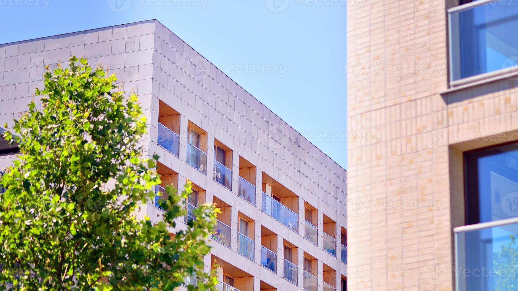 City life, urban landscape and ecology. Modern office complex with glass facades and smooth lines against backdrop of green trees, concept of modern architecture. Organically building into nature. photo