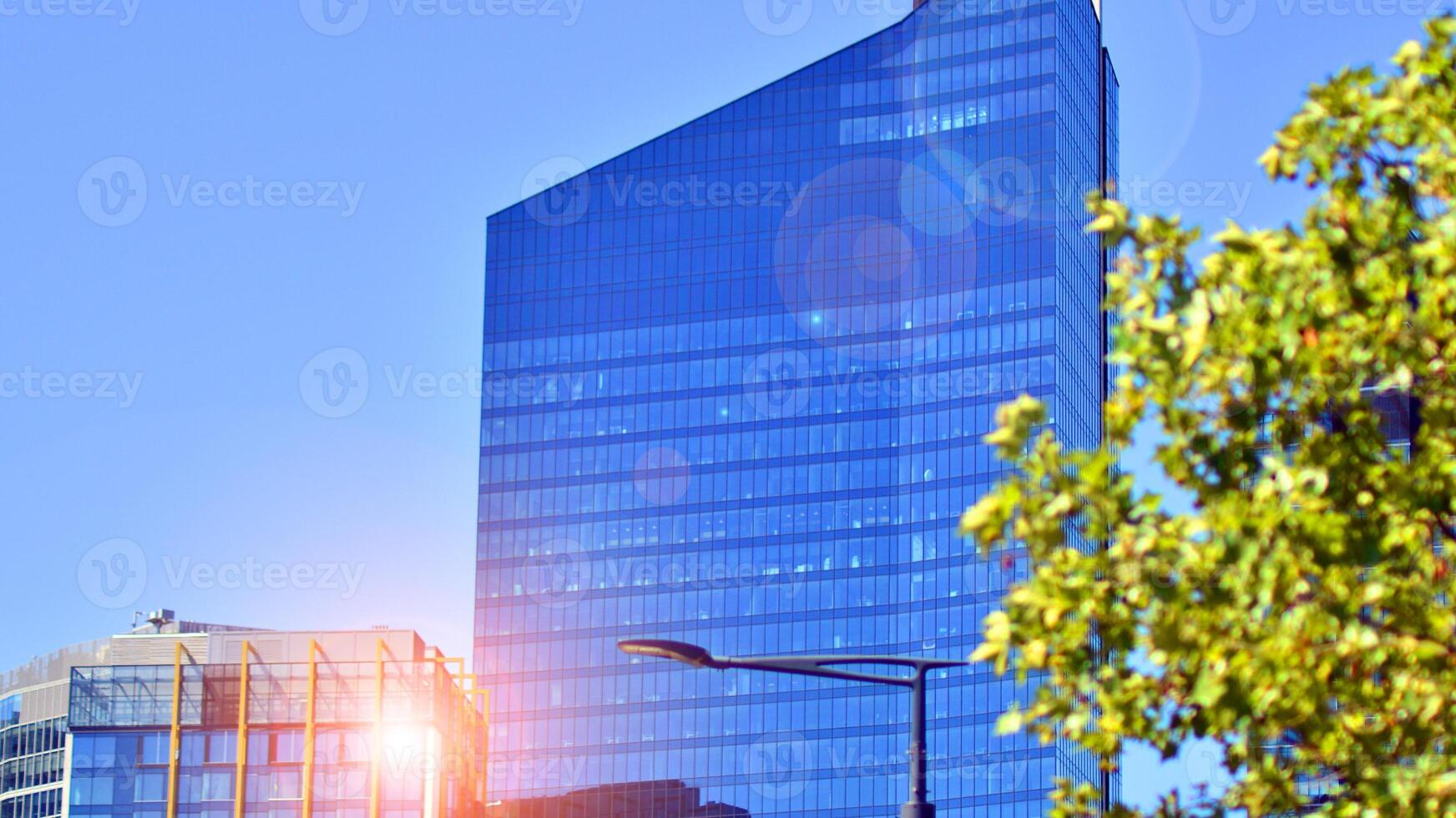 City life, urban landscape and ecology. Modern office complex with glass facades and smooth lines against backdrop of green trees, concept of modern architecture. Organically building into nature. photo