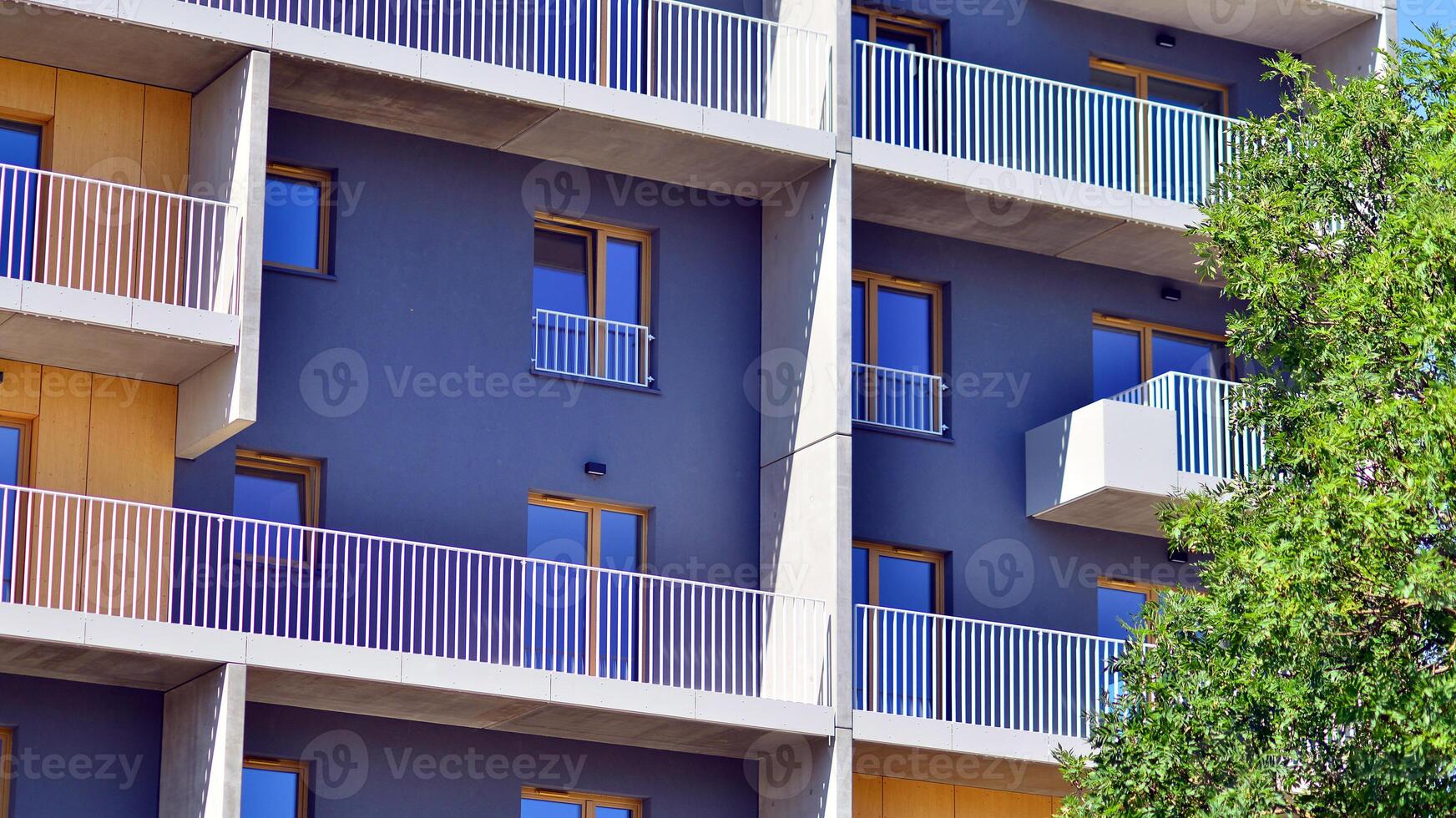 New modern block of flats in green area. Eco apartment building saving energy and fresh air concept. Green tree and new apartment building. The harmony of nature and modernity. photo