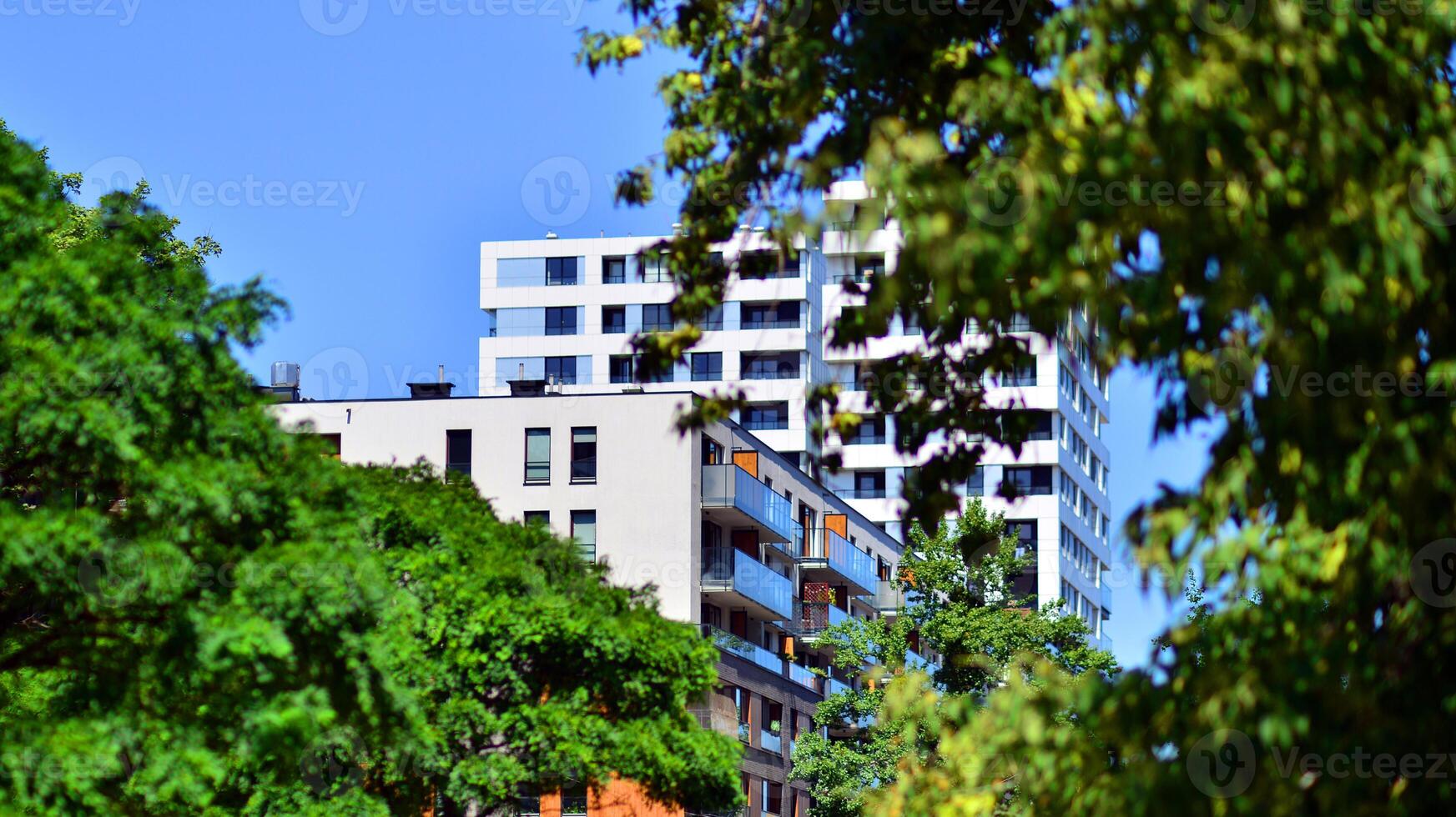 New modern block of flats in green area. Eco apartment building saving energy and fresh air concept. Green tree and new apartment building. The harmony of nature and modernity. photo