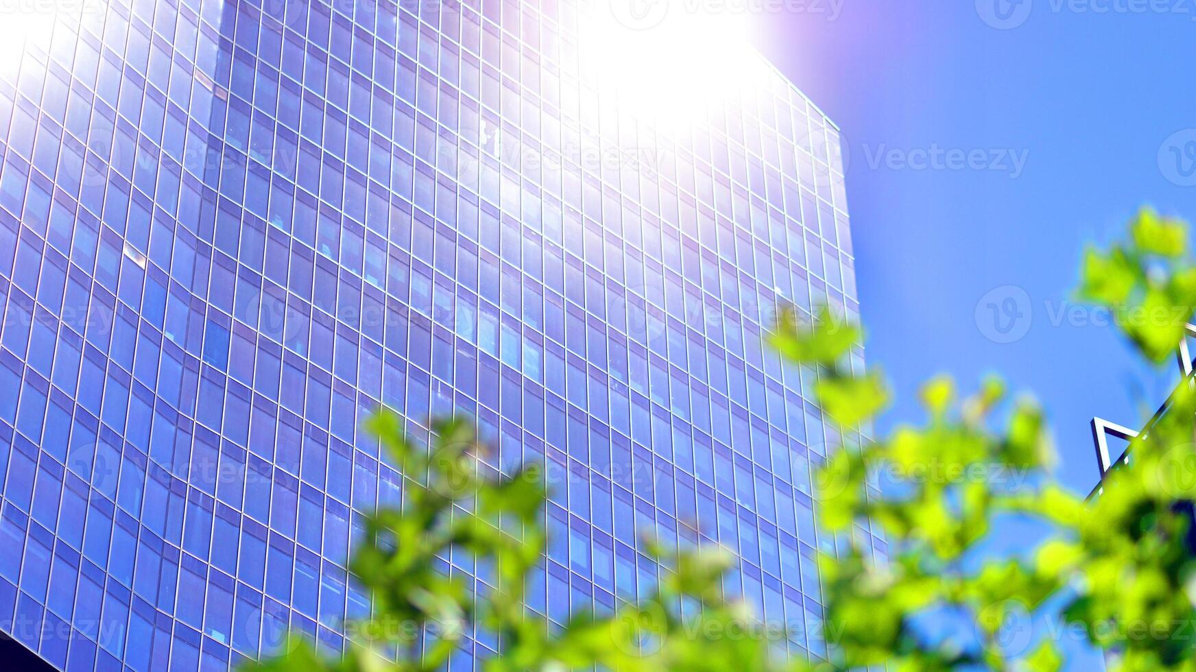 City life, urban landscape and ecology. Modern office complex with glass facades and smooth lines against backdrop of green trees, concept of modern architecture. Organically building into nature. photo