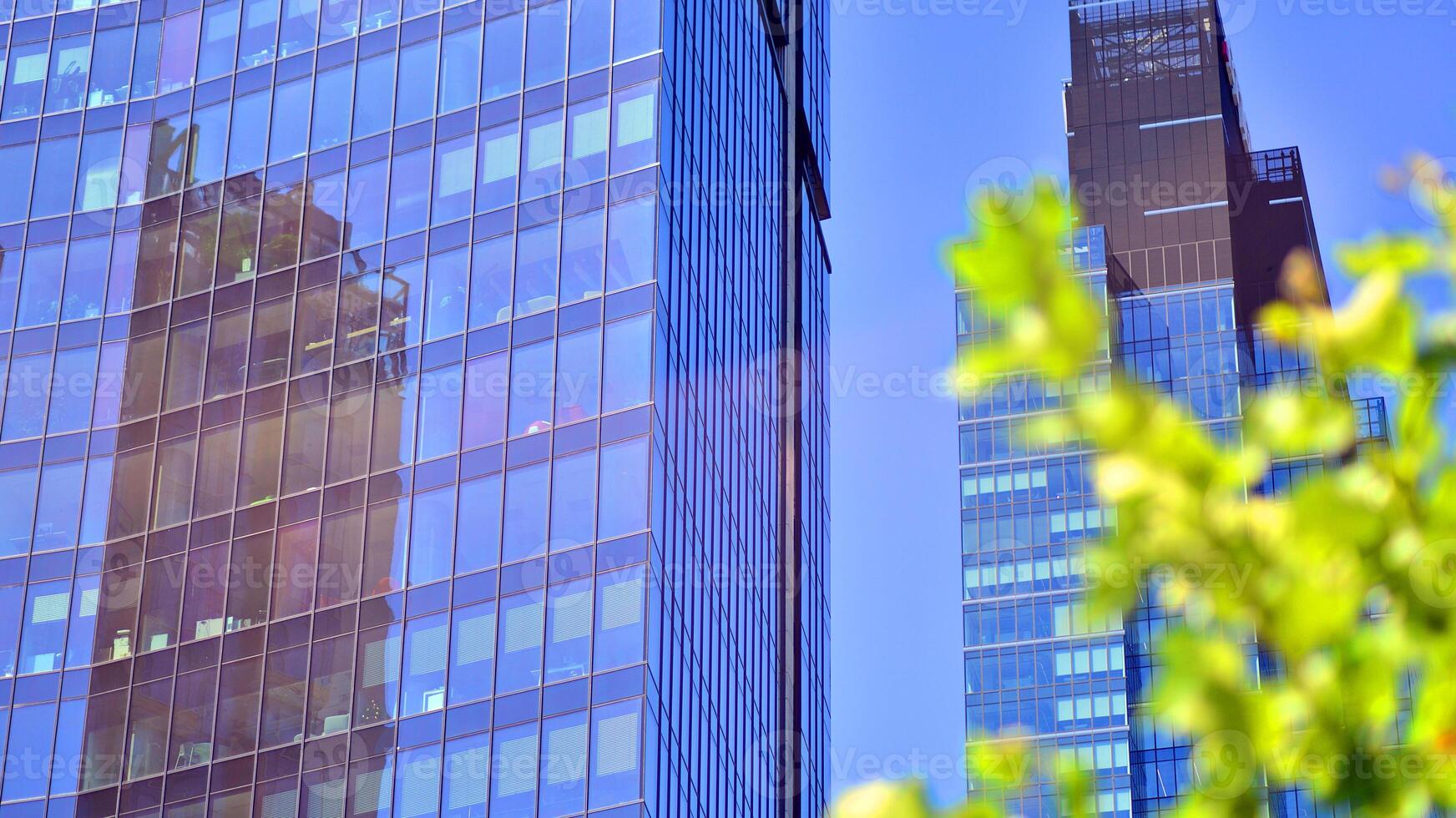 City life, urban landscape and ecology. Modern office complex with glass facades and smooth lines against backdrop of green trees, concept of modern architecture. Organically building into nature. photo