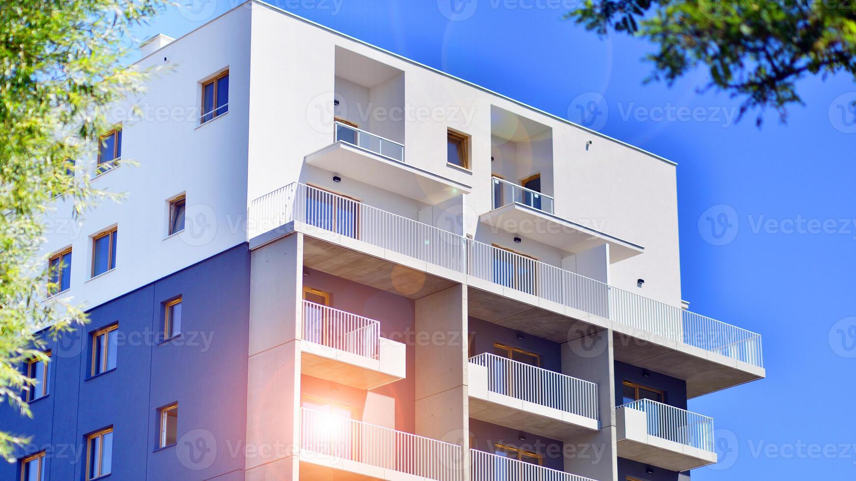 New modern block of flats in green area. Eco apartment building saving energy and fresh air concept. Green tree and new apartment building. The harmony of nature and modernity. photo