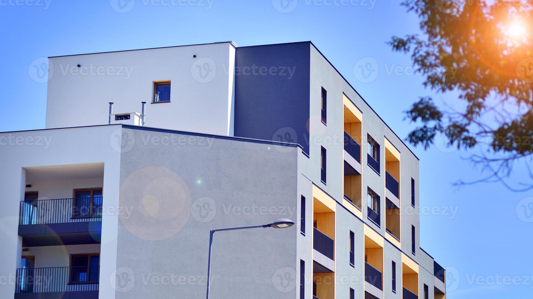 New modern block of flats in green area. Eco apartment building saving energy and fresh air concept. Green tree and new apartment building. The harmony of nature and modernity. photo