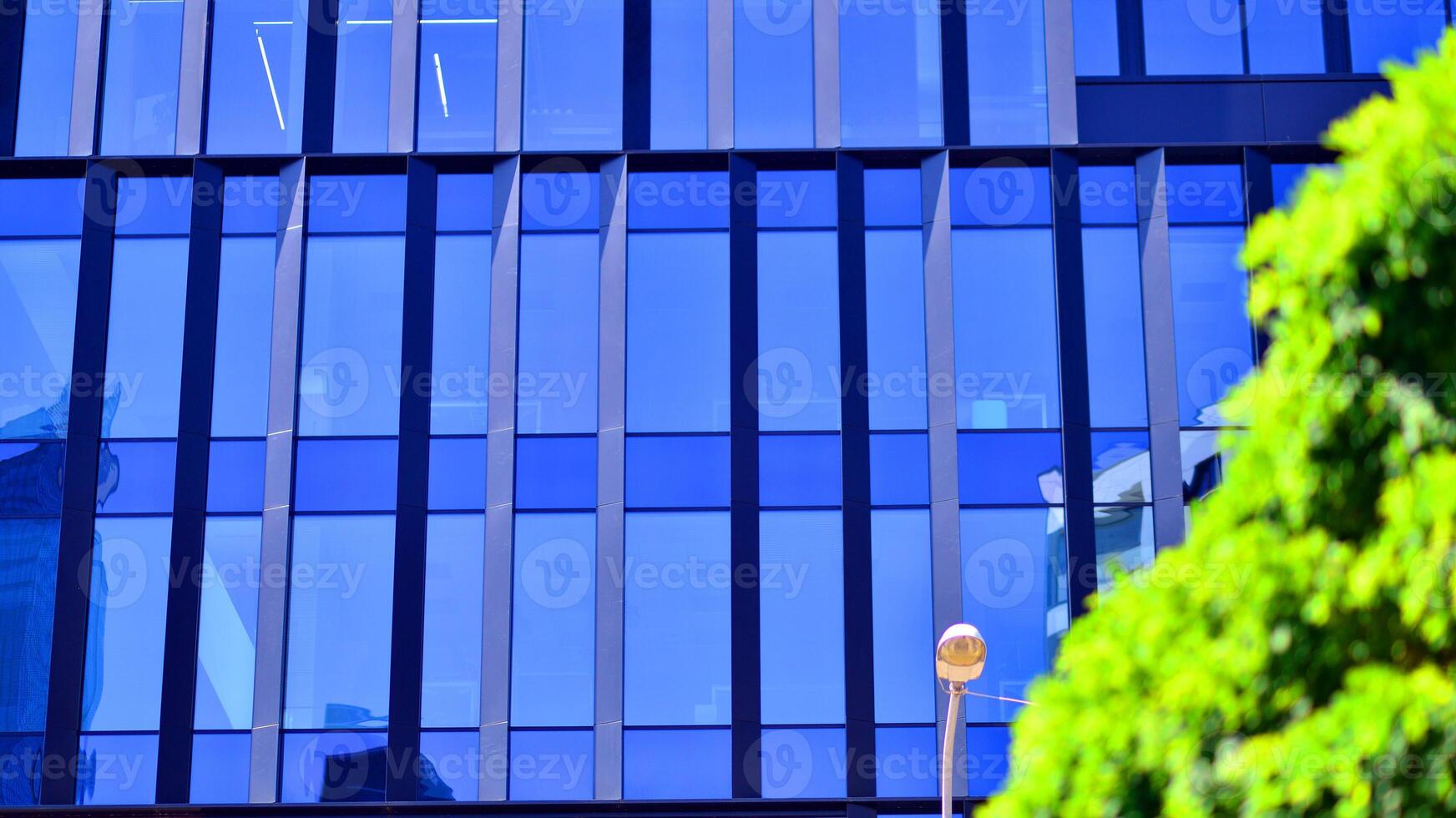 City life, urban landscape and ecology. Modern office complex with glass facades and smooth lines against backdrop of green trees, concept of modern architecture. Organically building into nature. photo