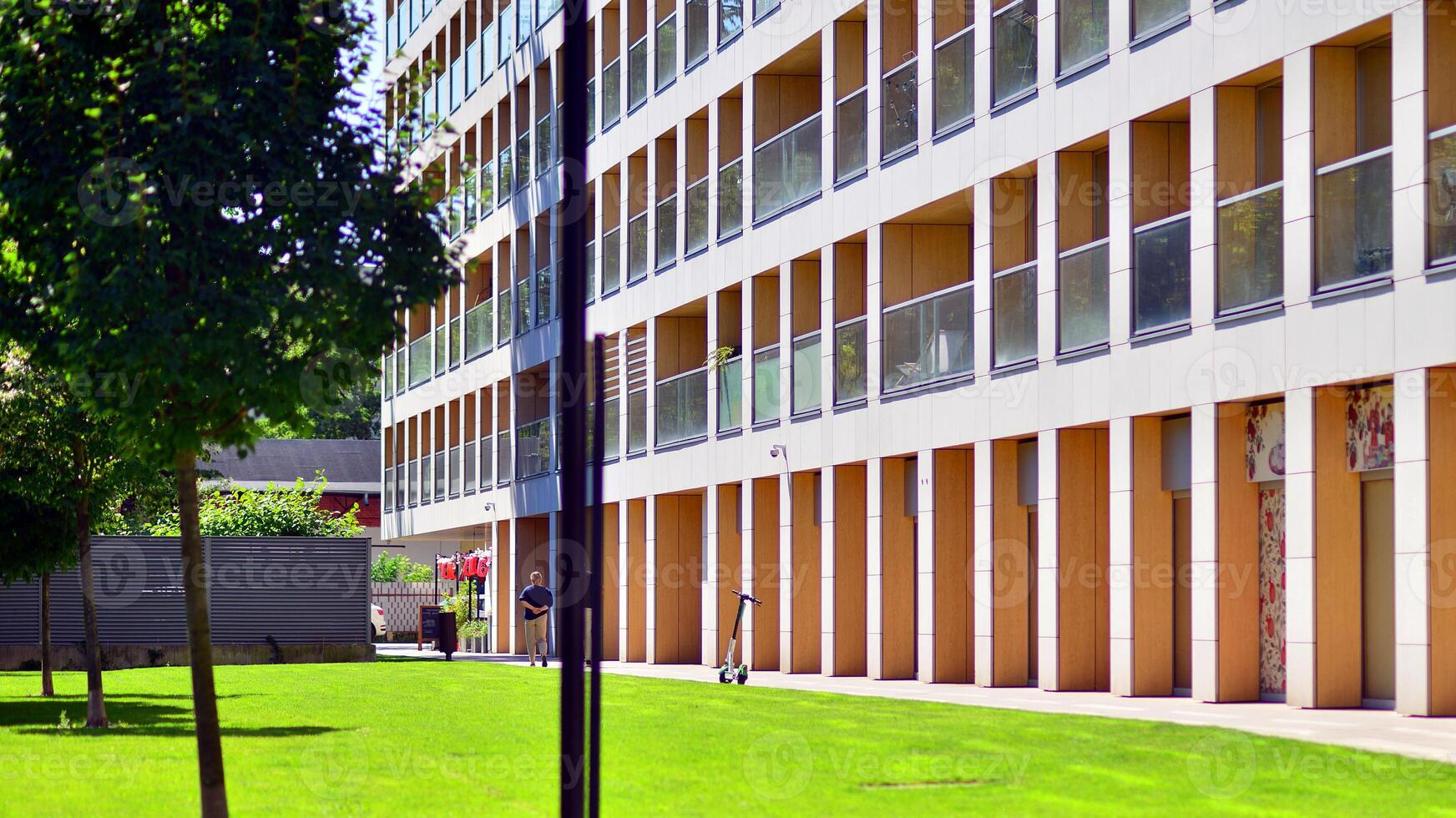 New modern block of flats in green area. Eco apartment building saving energy and fresh air concept. Green tree and new apartment building. The harmony of nature and modernity. photo