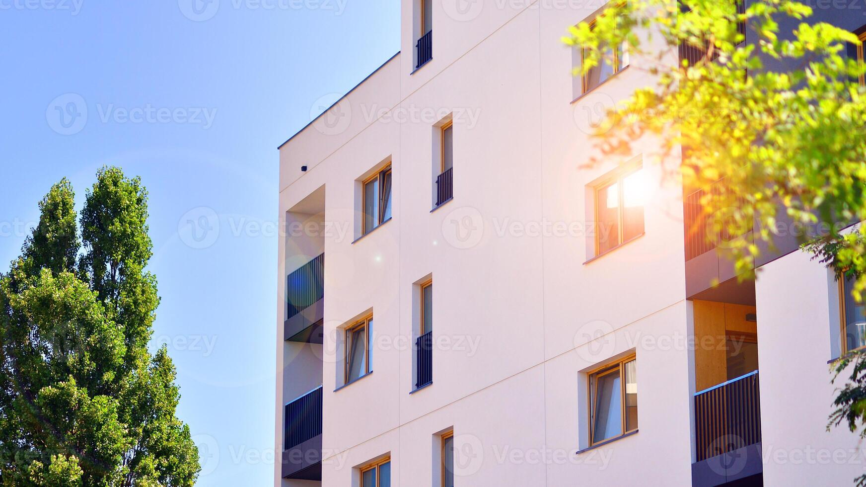 New modern block of flats in green area. Eco apartment building saving energy and fresh air concept. Green tree and new apartment building. The harmony of nature and modernity. photo