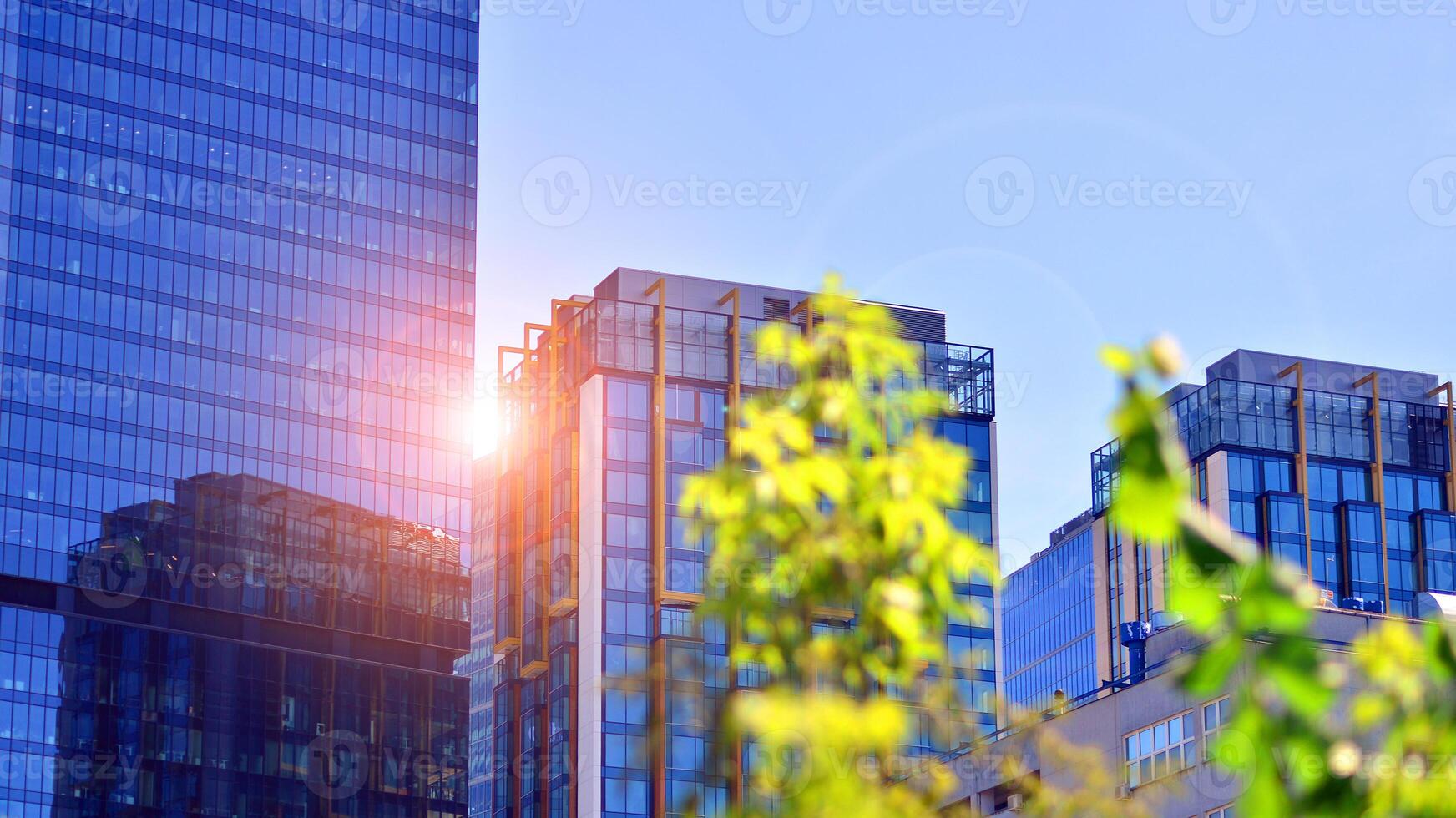 City life, urban landscape and ecology. Modern office complex with glass facades and smooth lines against backdrop of green trees, concept of modern architecture. Organically building into nature. photo