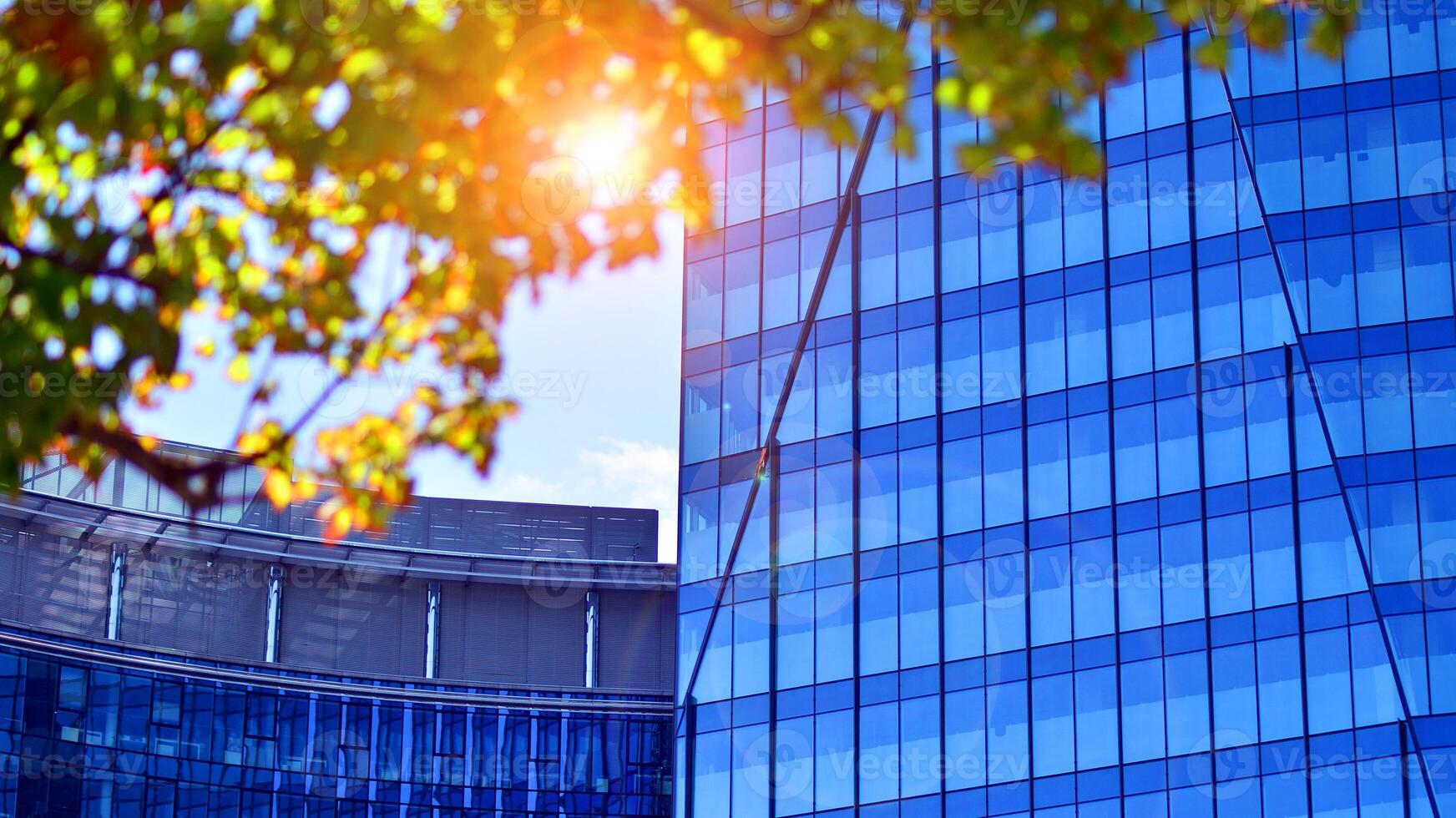 City life, urban landscape and ecology. Modern office complex with glass facades and smooth lines against backdrop of green trees, concept of modern architecture. Organically building into nature. photo