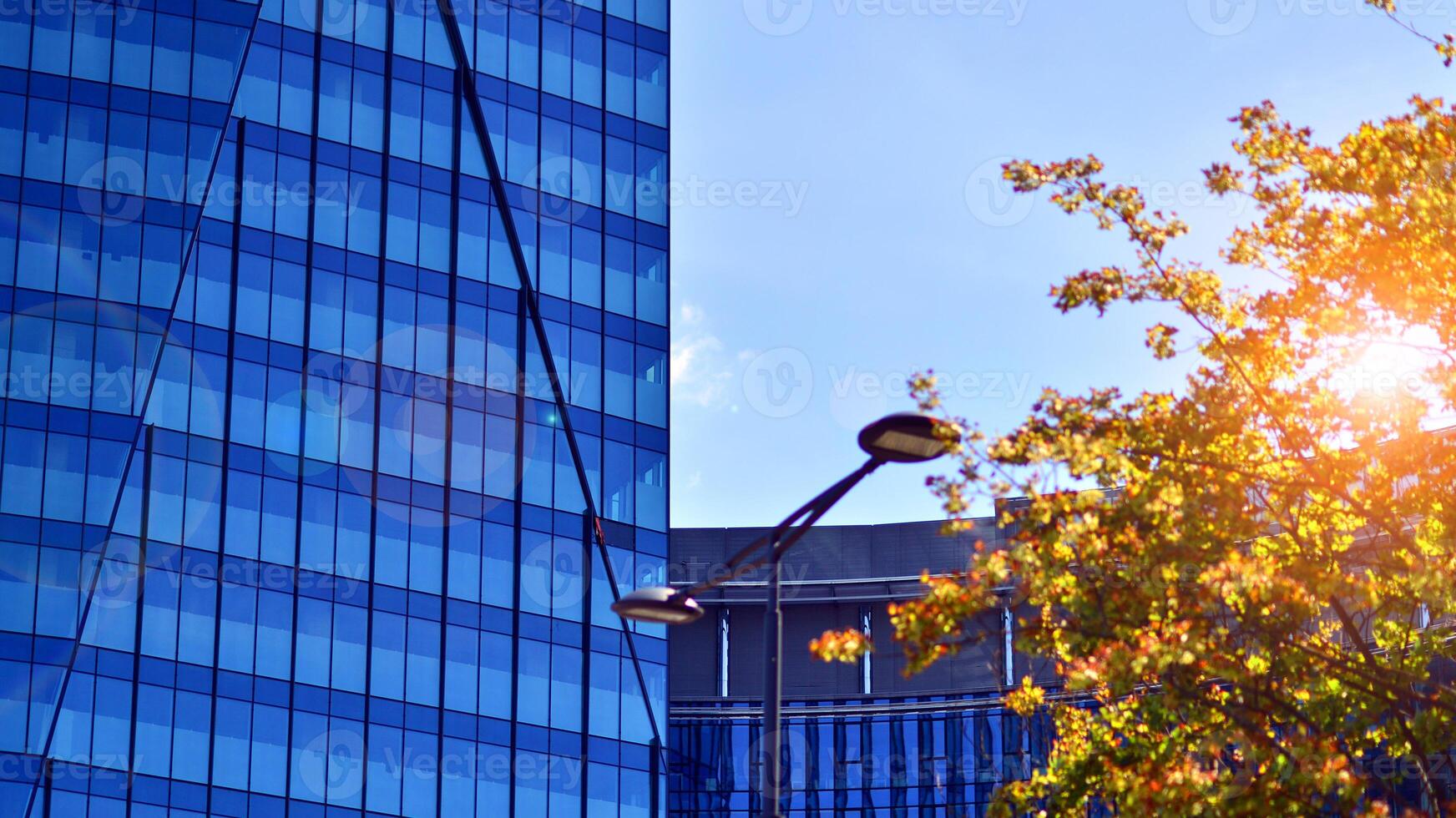 City life, urban landscape and ecology. Modern office complex with glass facades and smooth lines against backdrop of green trees, concept of modern architecture. Organically building into nature. photo
