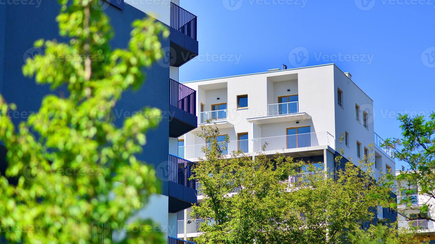 New modern block of flats in green area. Eco apartment building saving energy and fresh air concept. Green tree and new apartment building. The harmony of nature and modernity. photo