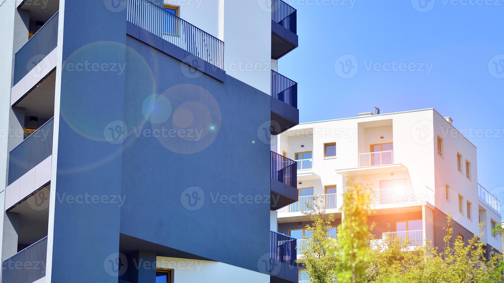 New modern block of flats in green area. Eco apartment building saving energy and fresh air concept. Green tree and new apartment building. The harmony of nature and modernity. photo