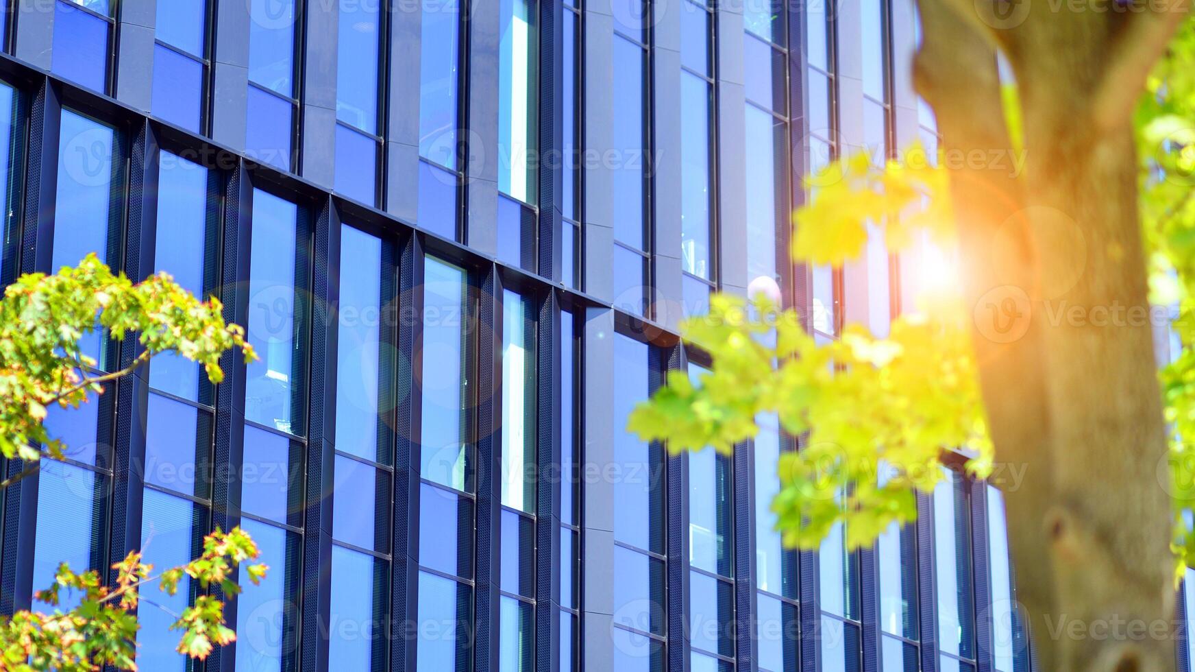 City life, urban landscape and ecology. Modern office complex with glass facades and smooth lines against backdrop of green trees, concept of modern architecture. Organically building into nature. photo