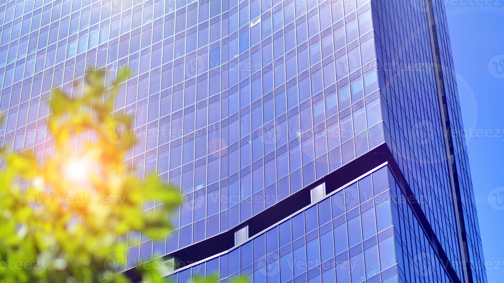 City life, urban landscape and ecology. Modern office complex with glass facades and smooth lines against backdrop of green trees, concept of modern architecture. Organically building into nature. photo