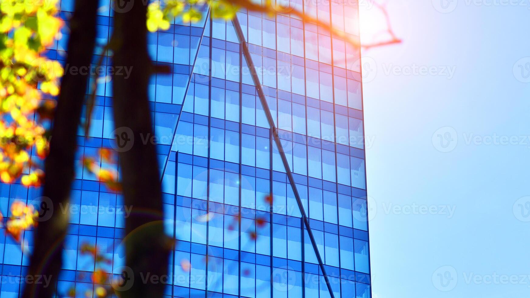 City life, urban landscape and ecology. Modern office complex with glass facades and smooth lines against backdrop of green trees, concept of modern architecture. Organically building into nature. photo