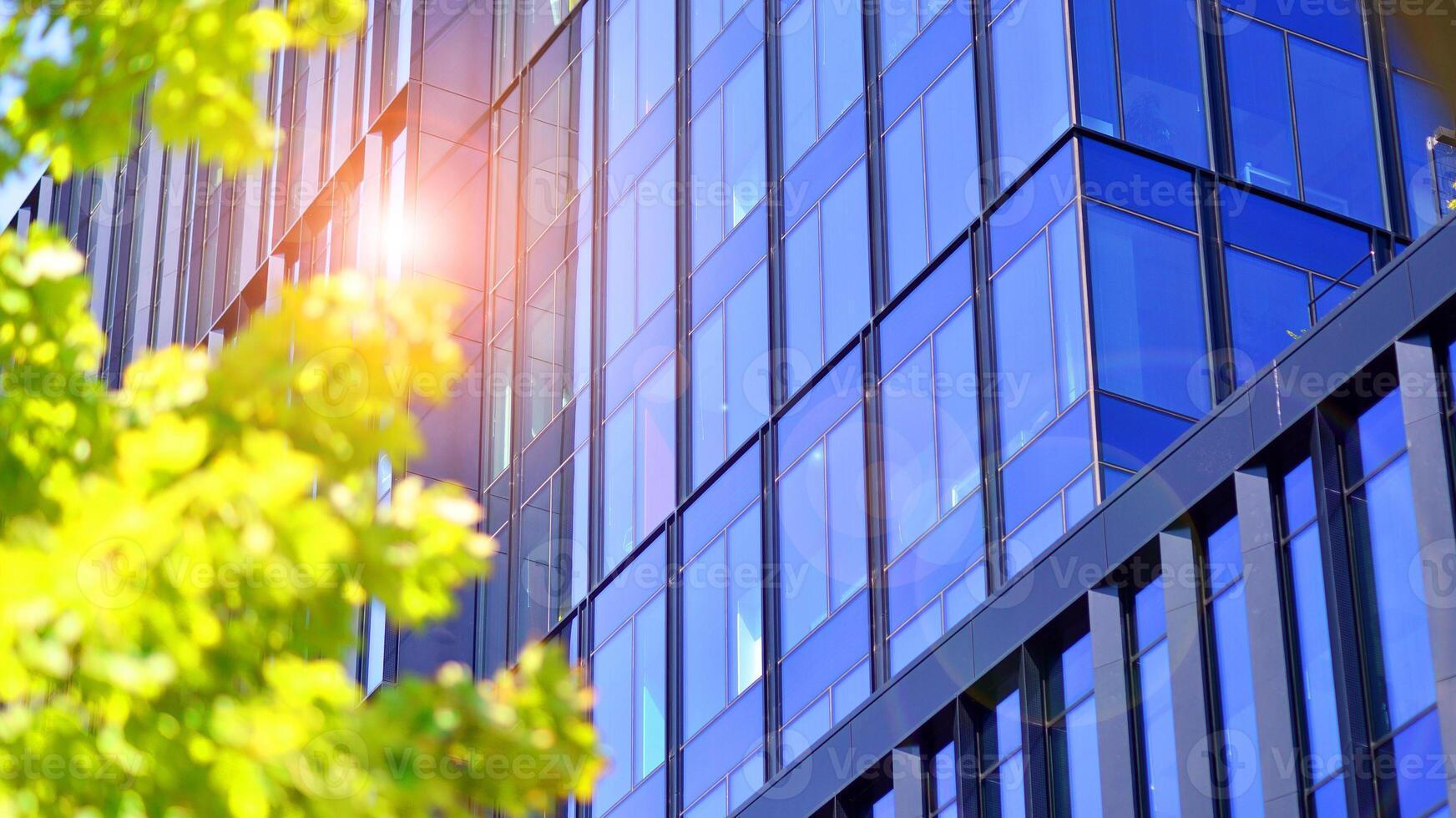 City life, urban landscape and ecology. Modern office complex with glass facades and smooth lines against backdrop of green trees, concept of modern architecture. Organically building into nature. photo