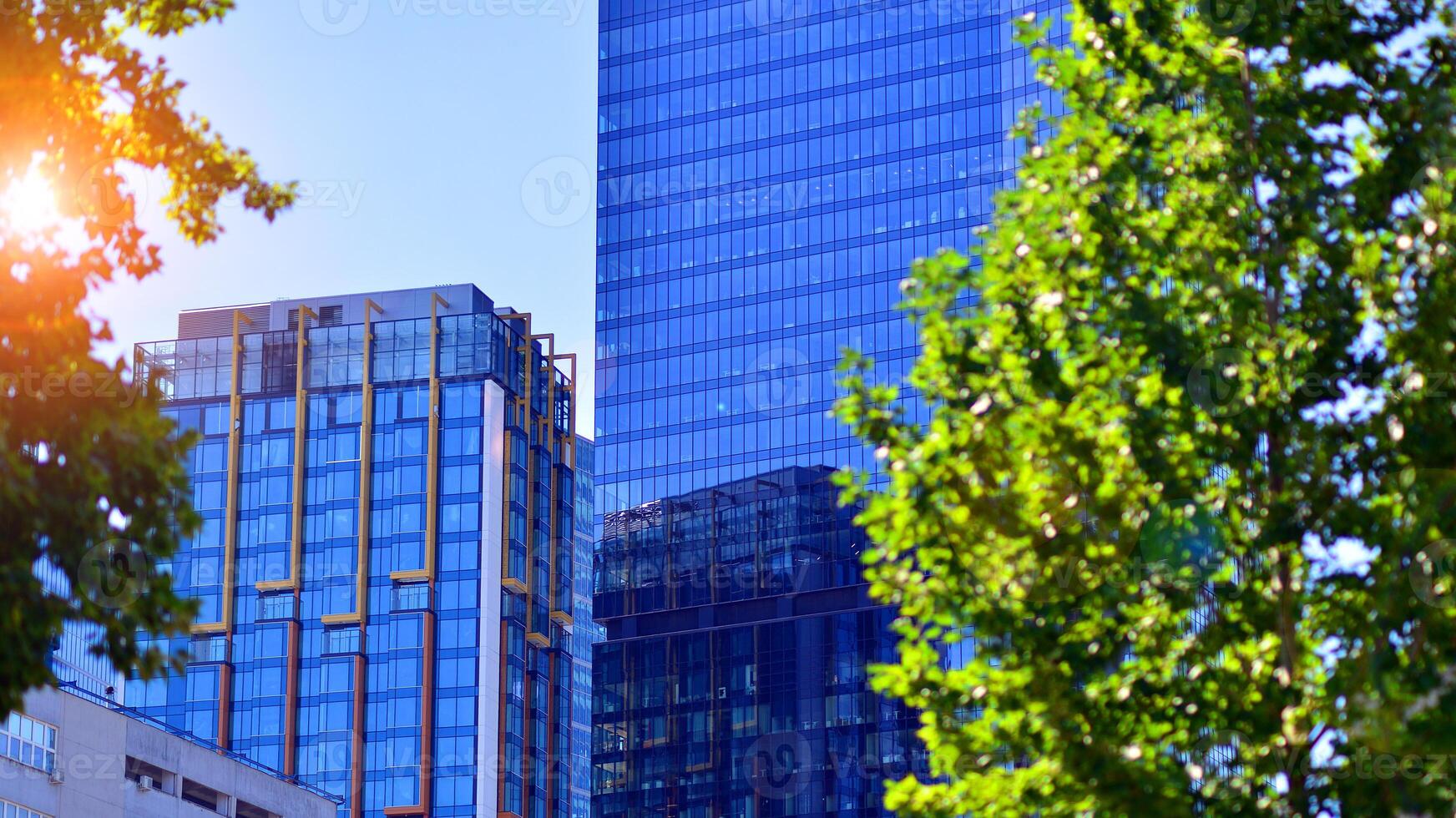 City life, urban landscape and ecology. Modern office complex with glass facades and smooth lines against backdrop of green trees, concept of modern architecture. Organically building into nature. photo