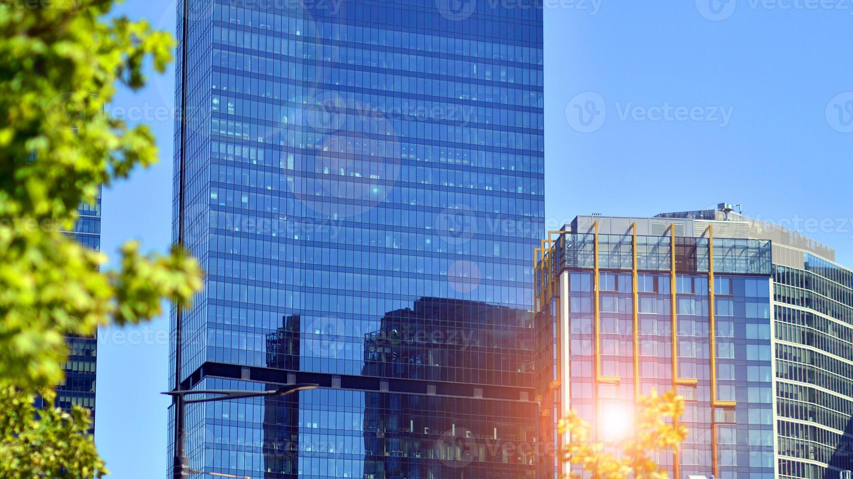City life, urban landscape and ecology. Modern office complex with glass facades and smooth lines against backdrop of green trees, concept of modern architecture. Organically building into nature. photo