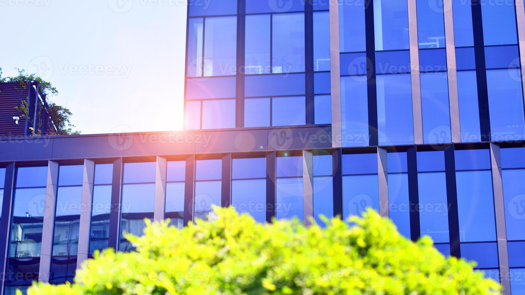 City life, urban landscape and ecology. Modern office complex with glass facades and smooth lines against backdrop of green trees, concept of modern architecture. Organically building into nature. photo