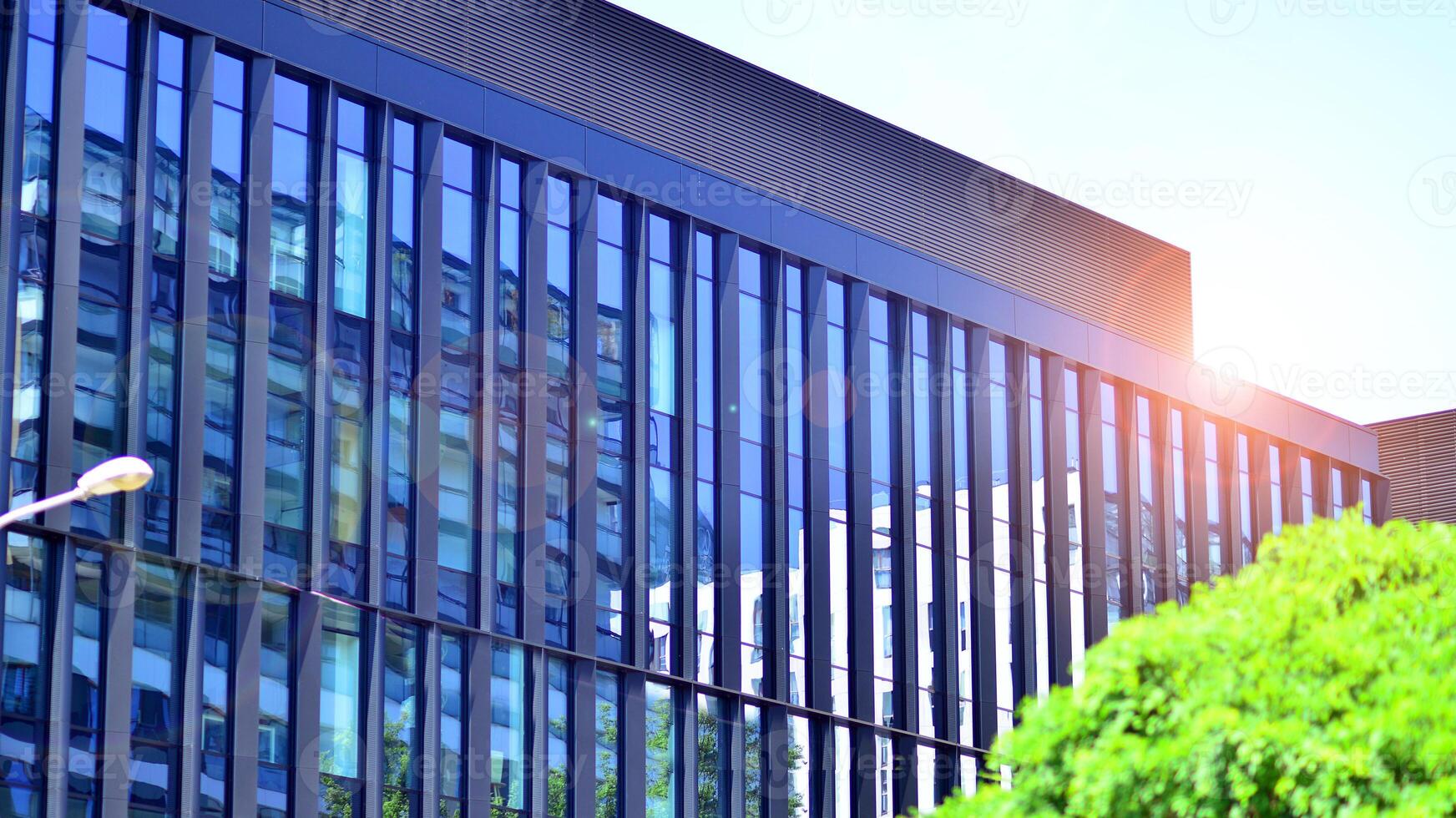 City life, urban landscape and ecology. Modern office complex with glass facades and smooth lines against backdrop of green trees, concept of modern architecture. Organically building into nature. photo