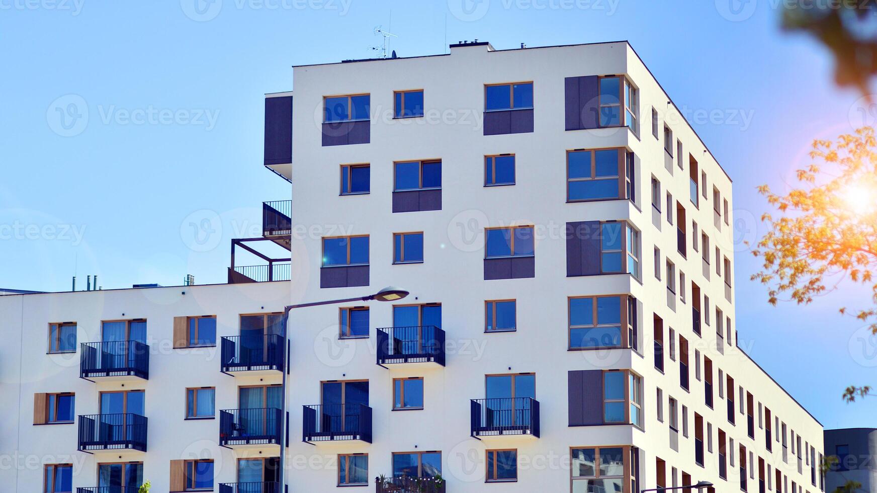 New modern block of flats in green area. Eco apartment building saving energy and fresh air concept. Green tree and new apartment building. The harmony of nature and modernity. photo