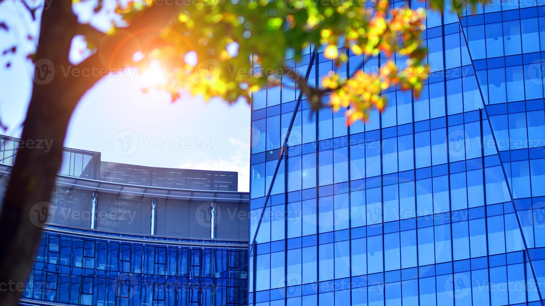 City life, urban landscape and ecology. Modern office complex with glass facades and smooth lines against backdrop of green trees, concept of modern architecture. Organically building into nature. photo