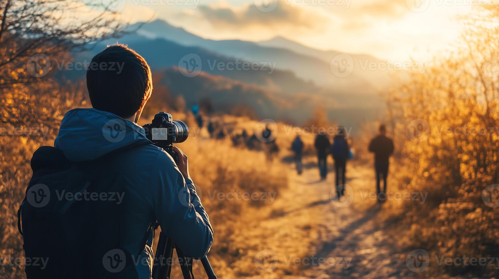 A photographer captures the golden hour light as hikers traverse a scenic mountain path photo