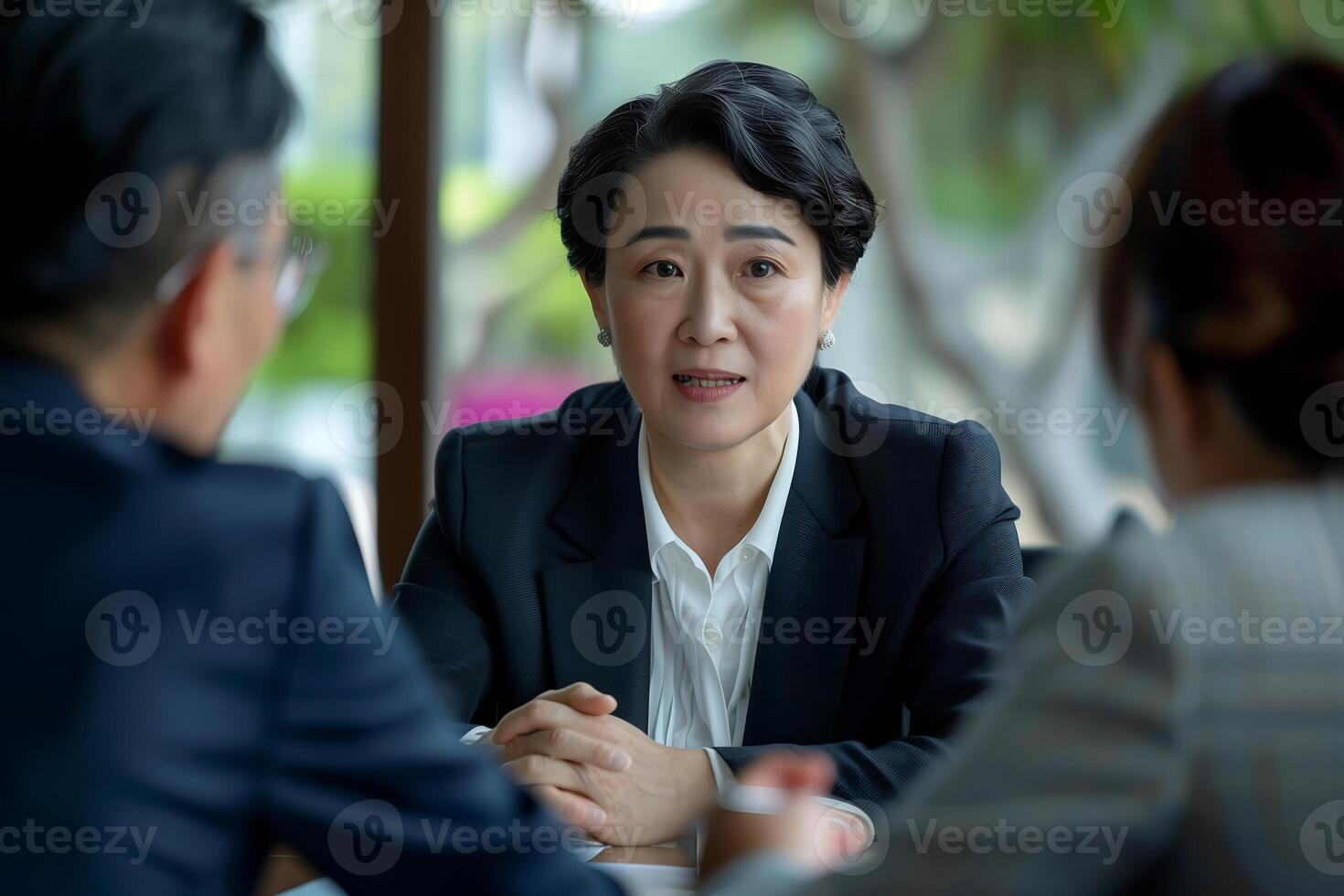 A businesswoman in a black suit is engaged in a conversation with her colleagues photo