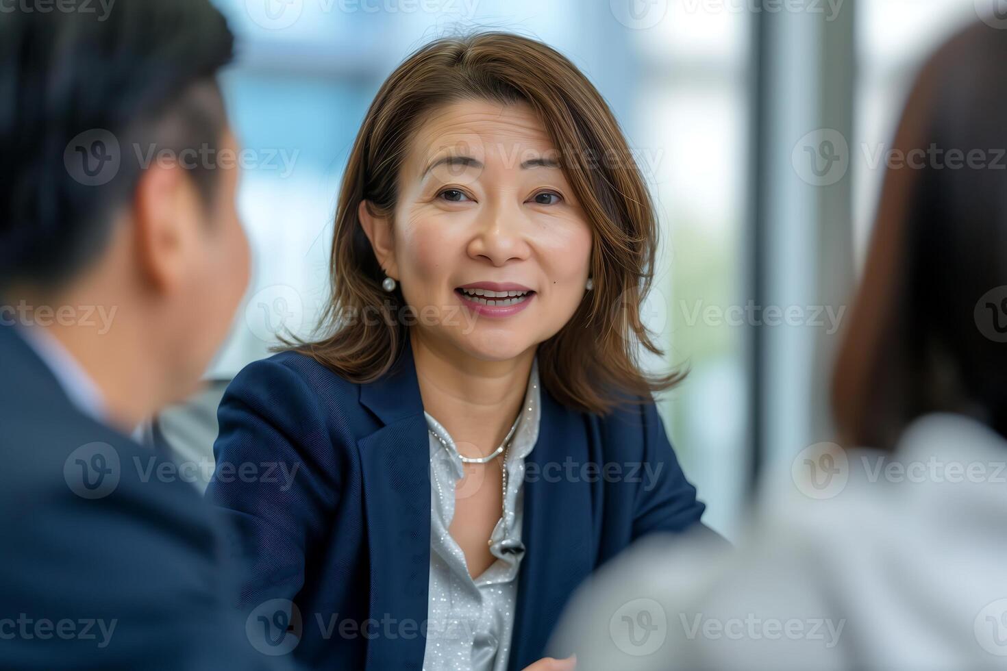 A businesswoman in a navy blazer engages in conversation with colleagues photo
