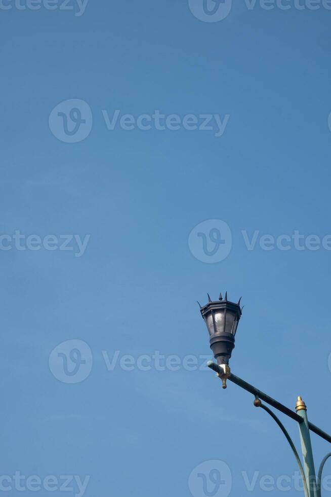 Vertical low angle shot of an old-fashioned traditional street lamp on a sunny day with a clear blue sky photo