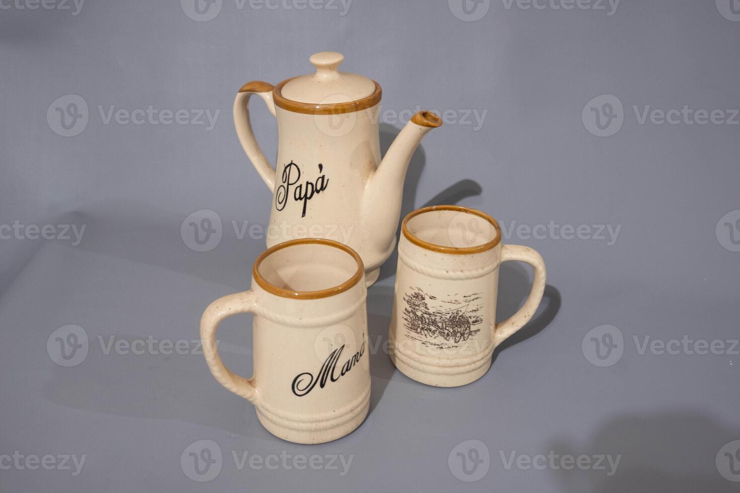 Ceramic teapot of cream colour and glass mug, unique design, kitchen utencil, isolated on grey background photo